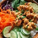A colorful Peanut Chicken Buddha Bowl with grilled chicken, quinoa, and fresh vegetables drizzled with peanut sauce.