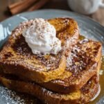 Golden brown slices of Pumpkin Spice French Toast topped with maple syrup and a dusting of cinnamon.