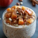 A bowl of creamy oatmeal topped with golden brown caramelised apples and a sprinkle of cinnamon.