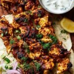 Skewers of grilled chicken shawarma with charred edges and golden spices on a platter.