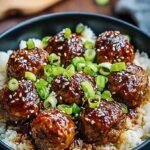 A golden baking dish filled with honey garlic meatballs, fluffy rice, and colorful peas and carrots.