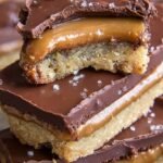 Homemade keto twix bars with layers of shortbread, caramel, and chocolate.