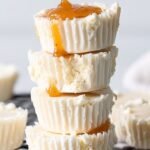 A tray of 12 creamy keto cheesecake fat bombs on parchment paper.