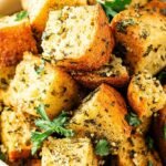 A close-up of golden brown, seasoned crispy keto croutons on a baking sheet.