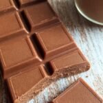 A close-up of smooth, homemade keto milk chocolate bars on a wooden board.