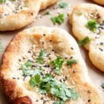 Golden brown keto garlic naan brushed with melted butter and fresh cilantro in a cast iron skillet
