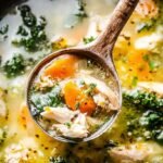 A steaming bowl of Keto Chicken Cauliflower Rice Soup garnished with fresh parsley in a rustic kitchen setting.