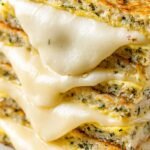 A golden brown sourdough grilled cheese sandwich filled with melted white cheddar and sautéed zucchini rounds.