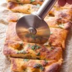 Golden brown keto garlic bread with melted butter, minced garlic, and fresh parsley on a baking sheet.