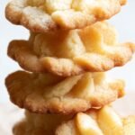 Golden keto butter spritz cookies in festive holiday shapes on a cooling rack.