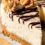 A slice of creamy peanut butter cheesecake with a dark chocolate crust on a white plate.