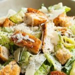 Fresh Keto Caesar Salad in a bowl topped with shaved parmesan and golden cheese crisps