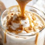 A bowl of creamy peanut butter yogurt topped with banana slices and cinnamon.