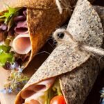 Freshly cooked golden flaxseed wraps stacked on a plate with a kitchen towel.