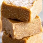 Squares of creamy keto peanut butter fudge on a wooden board with parchment paper