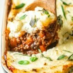 A golden brown Keto Cottage Pie in a ceramic dish with melted cheddar cheese and decorative cauliflower mash ridges.