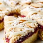 A golden brown Keto Bakewell Tart topped with flaked almonds and a raspberry jam layer.