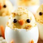 Cute deviled egg chicks with carrot beaks and olive eyes on a platter