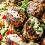 Golden brown keto cauliflower falafel balls served on a baking sheet with fresh herbs.