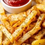 Golden brown and crispy air fryer turnip fries seasoned with smoked paprika and garlic on a white plate.