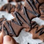 A tray of keto mummy cookies with cream cheese bandages and chocolate chip eyes on a dark background.
