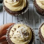 Six chocolate cupcakes with creamy white frosting on a wire cooling rack