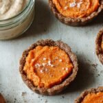Mini sweet potato tarts in a muffin tin with a golden almond flour crust and smooth orange filling