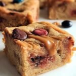 A stack of chewy peanut butter protein blondies with mini chocolate chips in a baking pan.