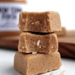 A close up of square pieces of Biscoff protein fudge on a wooden board.