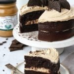 A moist chocolate protein cake with white frosting and crushed chocolate sandwich cookies on top.