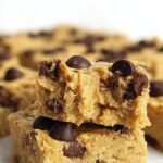 A stack of fudgy chocolate chip blondies made with chickpeas on parchment paper.