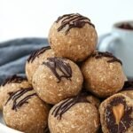 A plate of round chocolate peanut butter protein balls on a parchment-lined tray.
