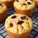 Six golden brown coconut flour protein muffins in silicone liners on a cooling rack.