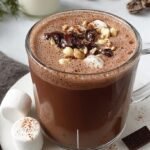 Two mugs of creamy sugar-free hot chocolate topped with whipped cream and cocoa powder