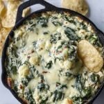 A golden brown baked cauliflower dip in a white ceramic dish with melted cheese on top