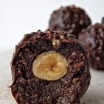 A plate of homemade chocolate hazelnut protein truffles coated in crushed nuts