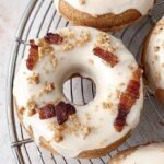Six baked protein donuts topped with maple glaze and crumbled bacon on a wire rack