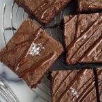 A stack of fudgy chocolate brownies made with black beans on a white plate.