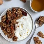 A tray of crunchy maple cinnamon granola broken into large clusters on parchment paper.