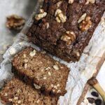 A sliced loaf of espresso banana bread topped with crunchy walnuts and oats on a wire rack.
