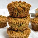 Golden brown peanut butter zucchini muffins with melted chocolate chips on a cooling rack.