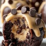 A stack of chocolate-dipped brownie bombs with one cut open to reveal a cookie dough center.