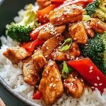 A bowl of glazed teriyaki chicken over white rice with green onions