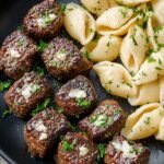 Seared garlic butter steak bites served over creamy parmesan pasta shells with fresh parsley