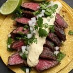Grilled steak tacos on corn tortillas drizzled with smoky chipotle crema and fresh cilantro.