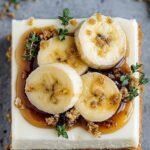 A creamy slice of crustless banana greek yogurt cheesecake on a white plate with fresh berries