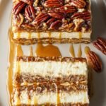Layers of cream cheese, pecan pie filling, and whipped cream in a glass baking dish.