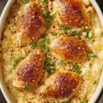 A creamy chicken and rice casserole in a white baking dish topped with savory onion soup mix.