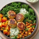 A colorful chicken meatball bowl with quinoa, cucumber salad, and Greek yogurt dollop