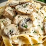 A white bowl filled with creamy chicken and mushroom tagliatelle topped with fresh parsley